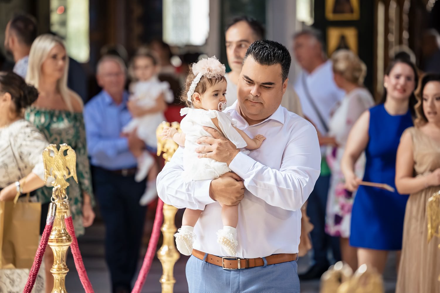 Φωτογράφηση βάπτισης διδύμων στη Λάρισα. Νονός κρατά το κοριτσάκι αγκαλιά μέσα στην εκκλησία πριν την τελετή.