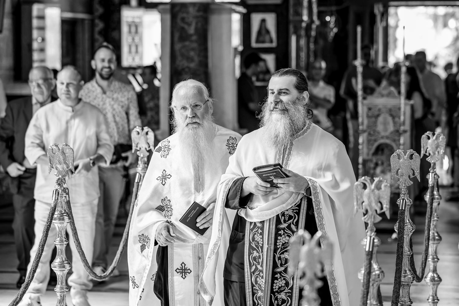 Φωτογράφηση βάπτισης διδύμων στη Λάρισα. Ασπρόμαυρη φωτογραφία δύο ιερέων σε πομπή μέσα στην εκκλησία.