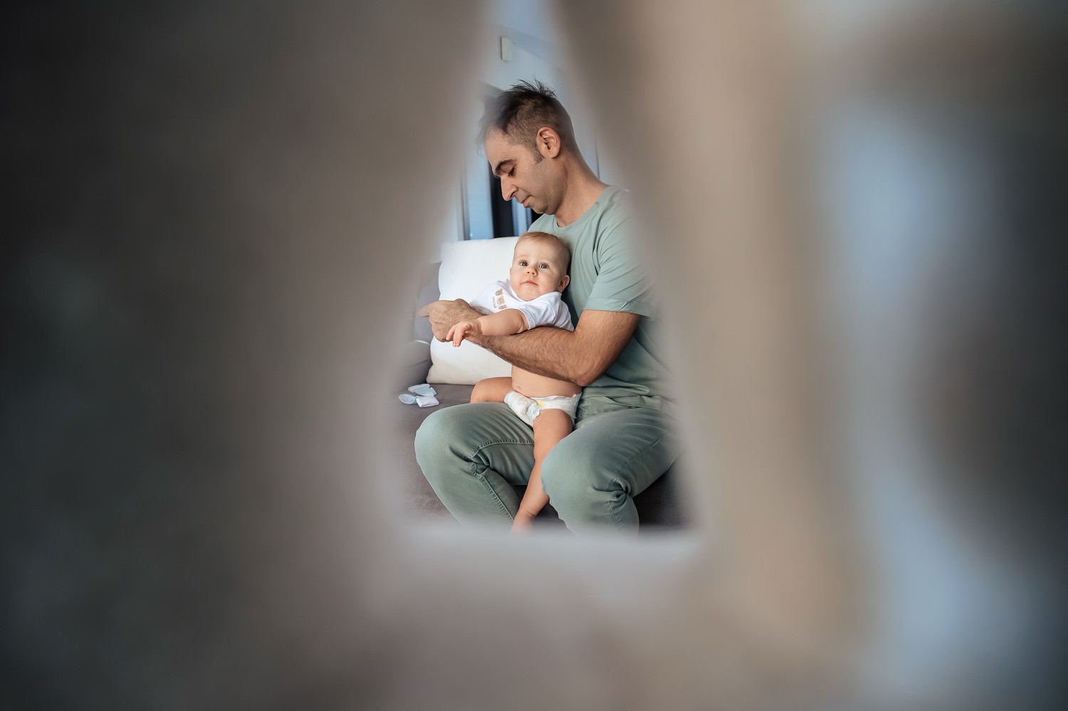 Προετοιμασία βάπτισης διδύμων στη Λάρισα. Πατέρας αγκαλιάζει το αγοράκι του στο σπίτι πριν το μυστήριο.